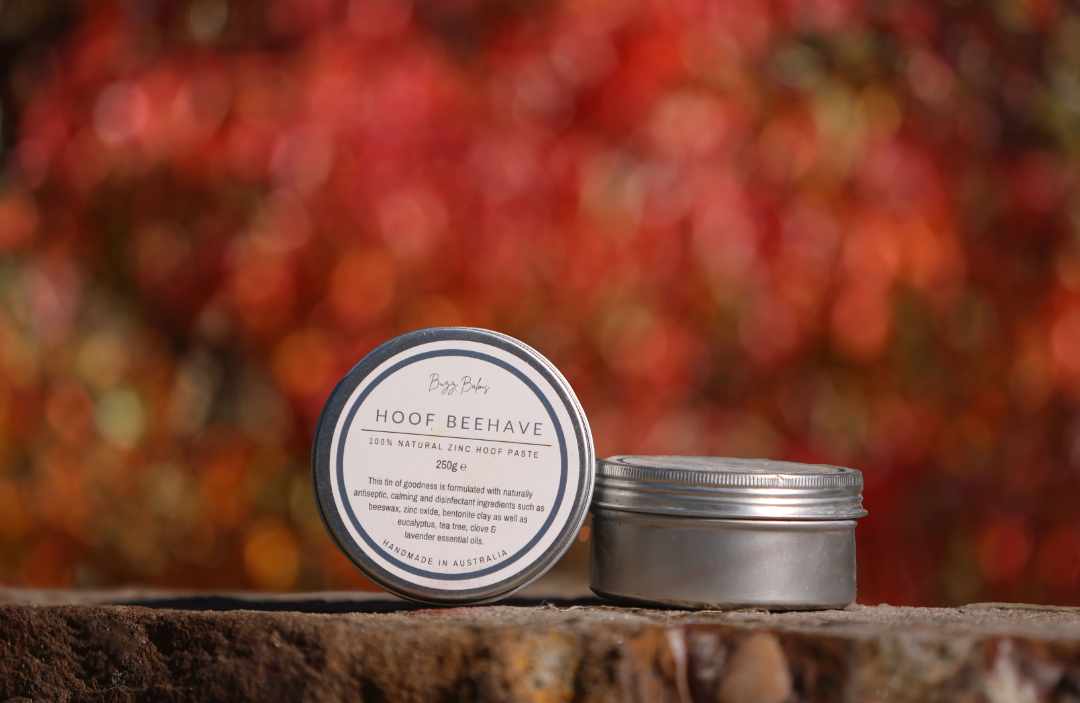 Metal tin labeled 'Hoof Beehave' on a wooden surface with a blurred autumn background.